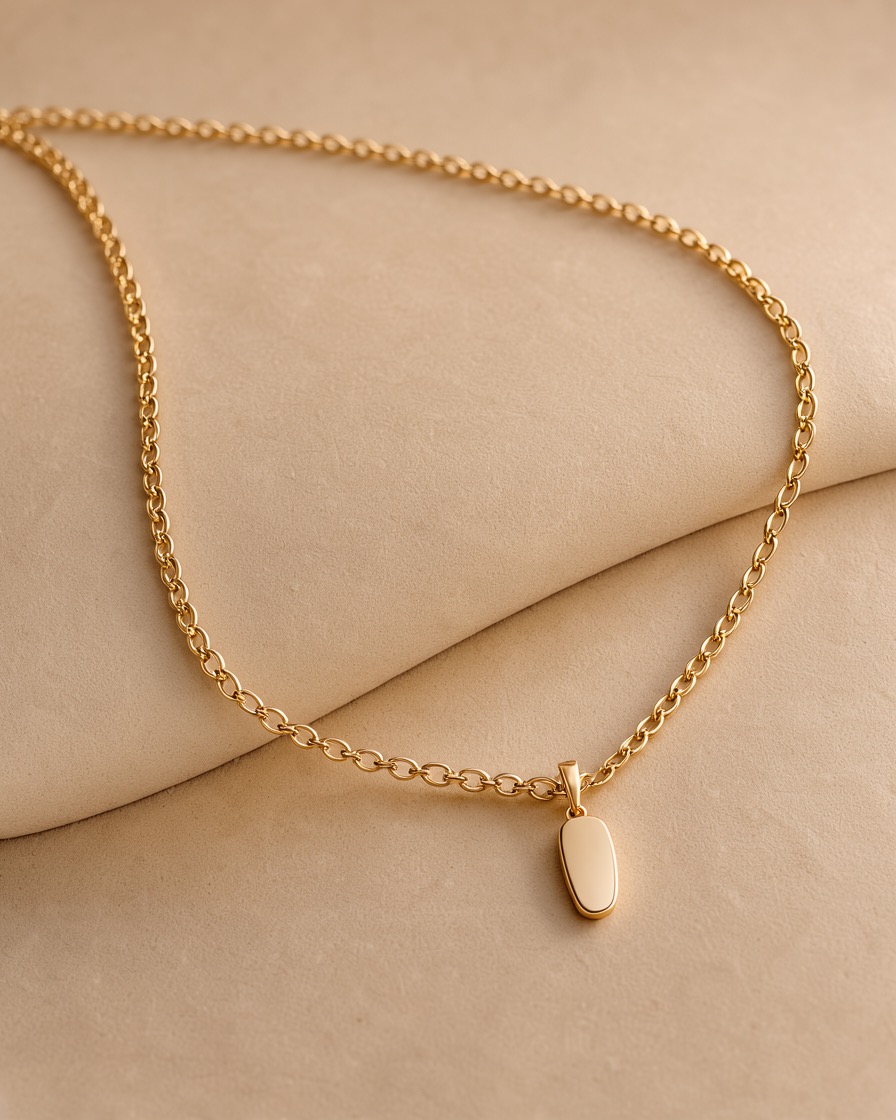 Fine gold chain necklace draped on a bone sweep with soft glow